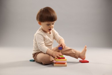 Cute little boy playing on grey background