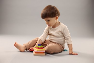 Cute little boy playing on grey background