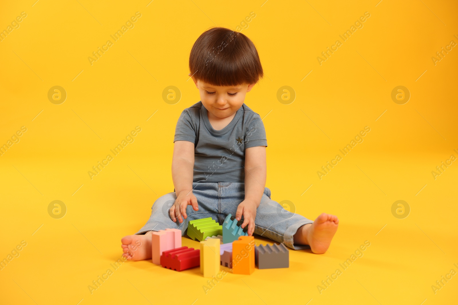 Photo of Cute little boy playing on yellow background