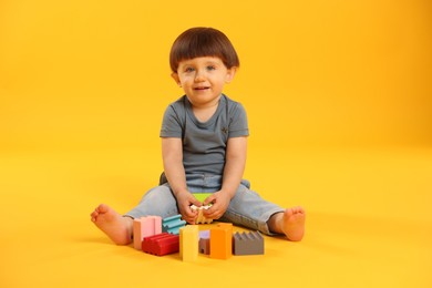 Cute little boy playing on yellow background