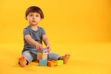 Photo of Cute little boy playing on yellow background. Space for text