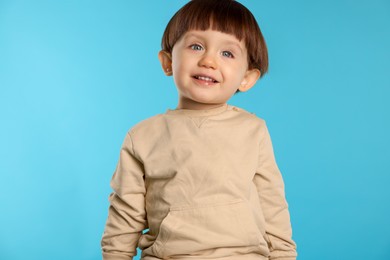 Portrait of happy little boy on light blue background