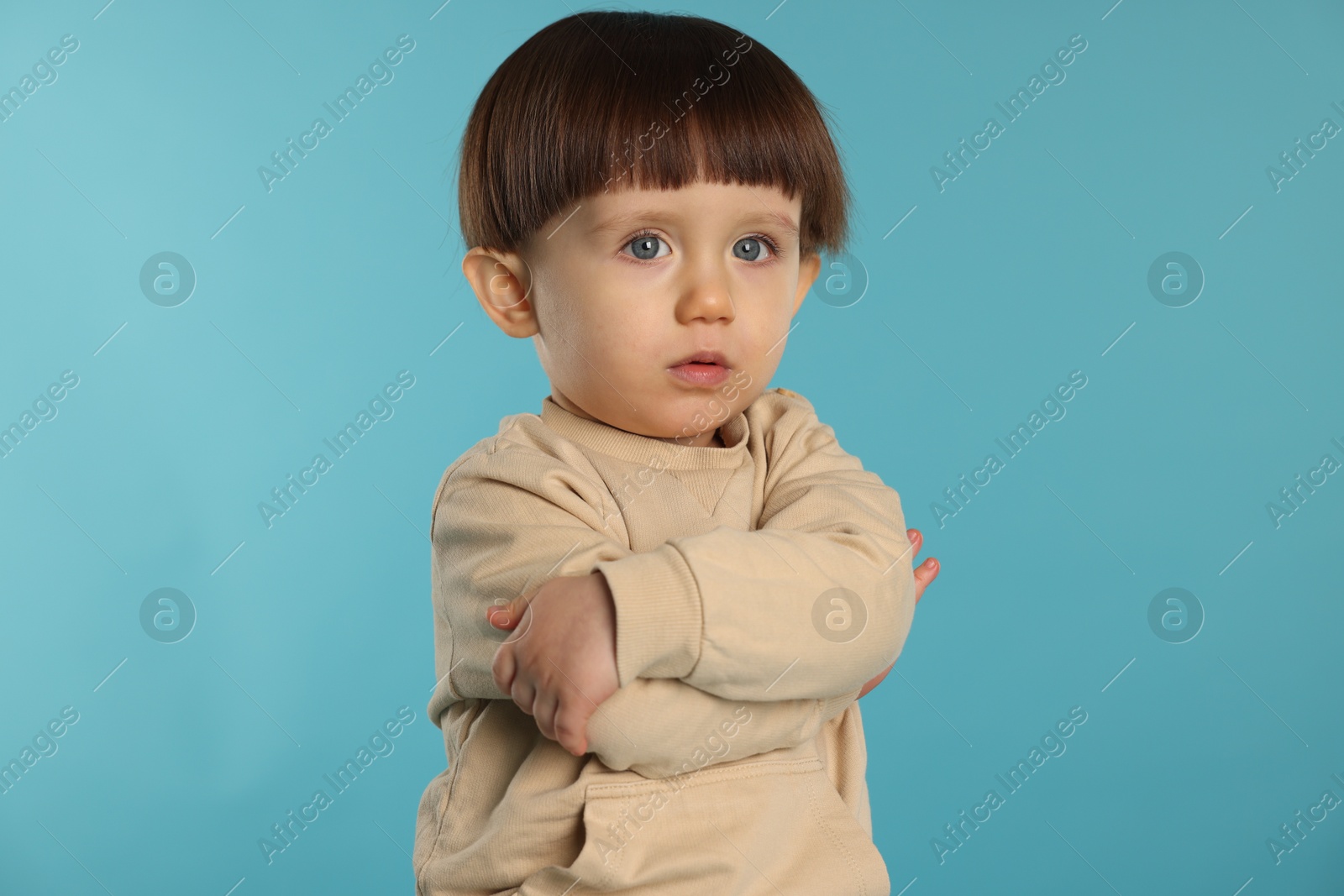 Photo of Portrait of cute little boy on light blue background