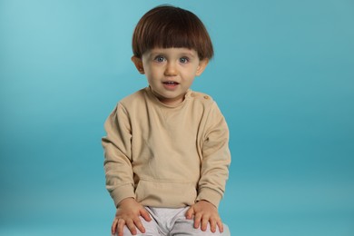 Photo of Portrait of cute little boy on light blue background