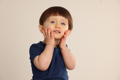 Portrait of cute little boy on light grey background