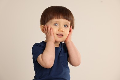 Portrait of cute little boy on light grey background