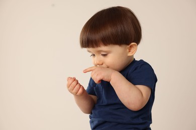 Photo of Portrait of cute little boy on light grey background. Space for text