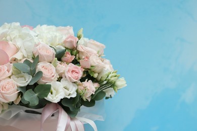 Photo of Bouquet of beautiful flowers and eucalyptus branches on light blue background, closeup. Space for text