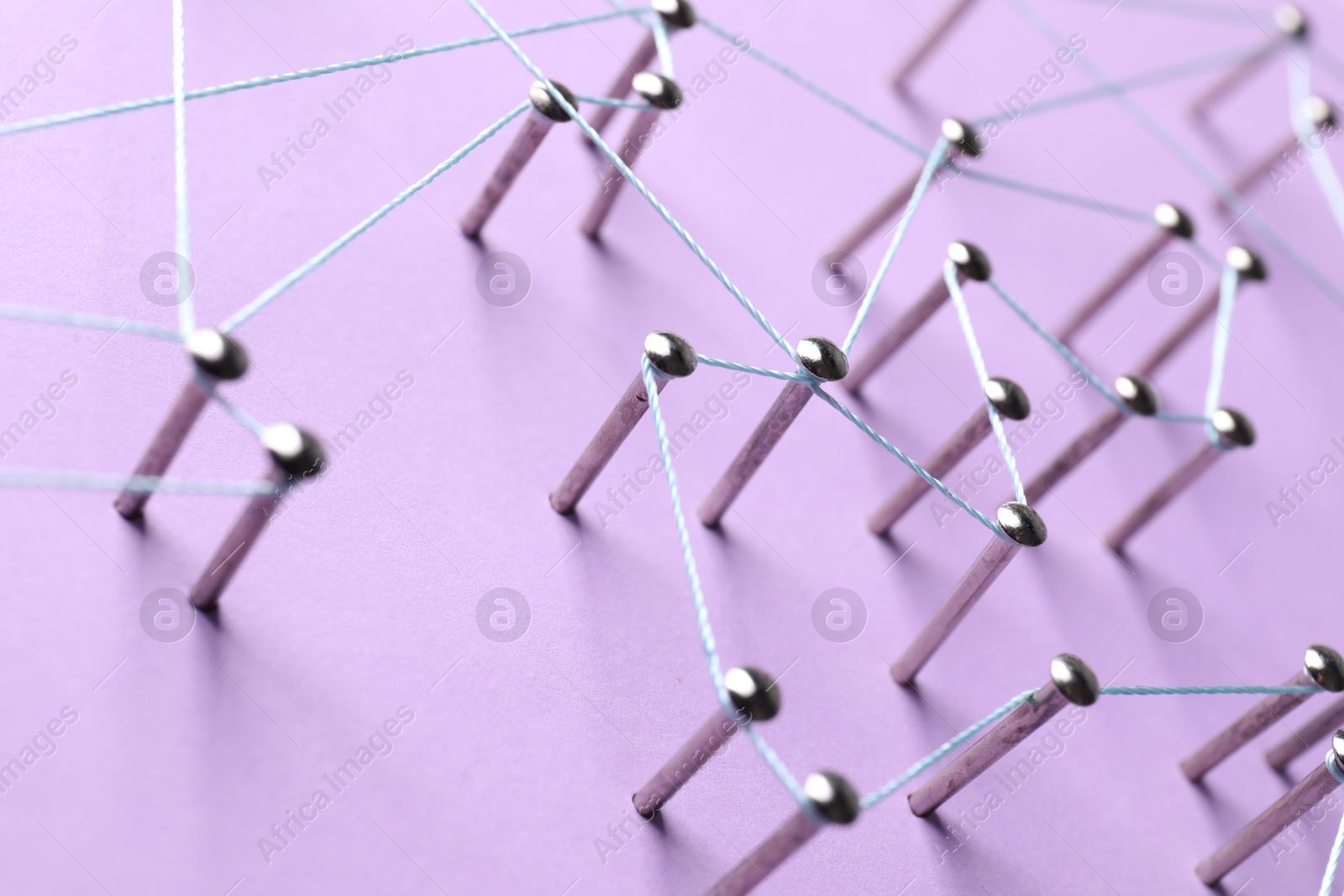 Photo of Network connection. Nails linked together by thread on violet background, closeup