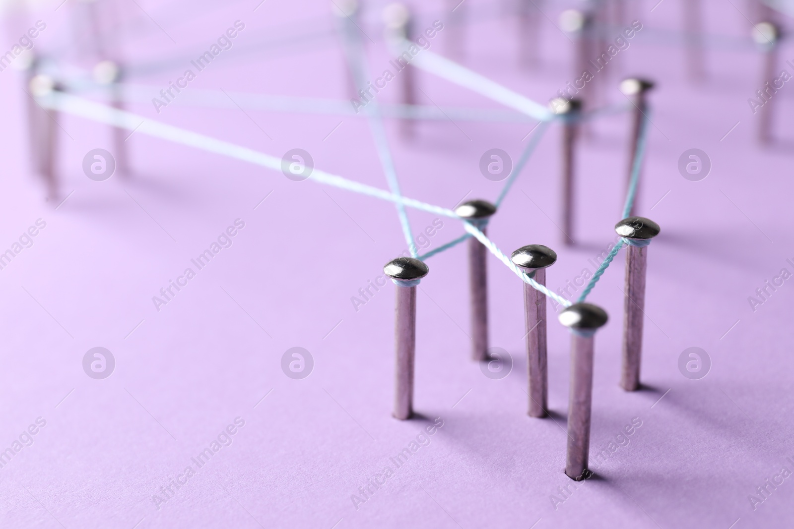 Photo of Network connection. Nails linked together by thread on violet background, closeup. Space for text