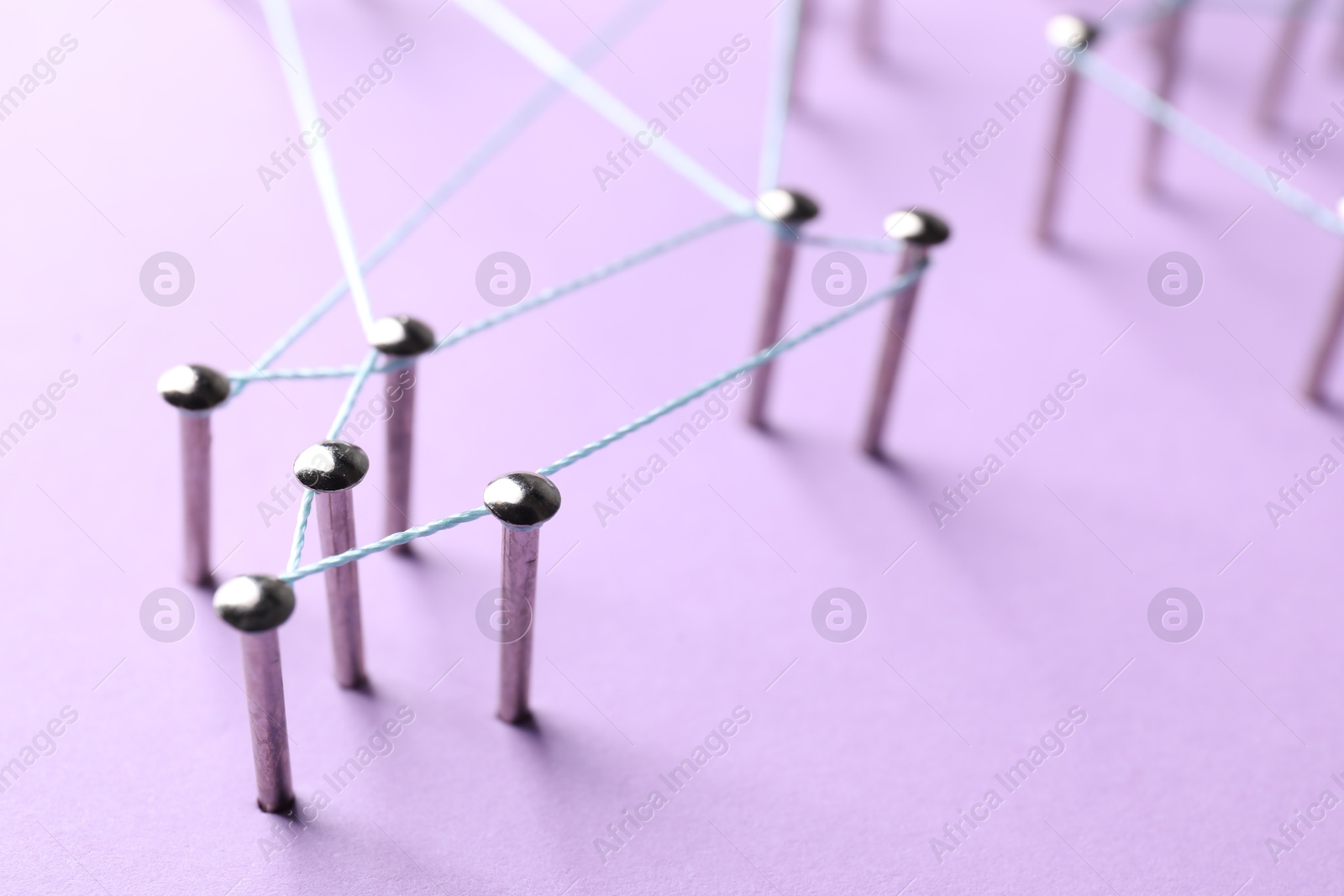 Photo of Network connection. Nails linked together by thread on violet background, closeup. Space for text