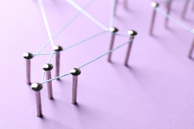 Photo of Network connection. Nails linked together by thread on violet background, closeup. Space for text