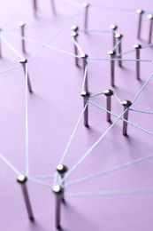 Photo of Network connection. Nails linked together by thread on violet background, closeup