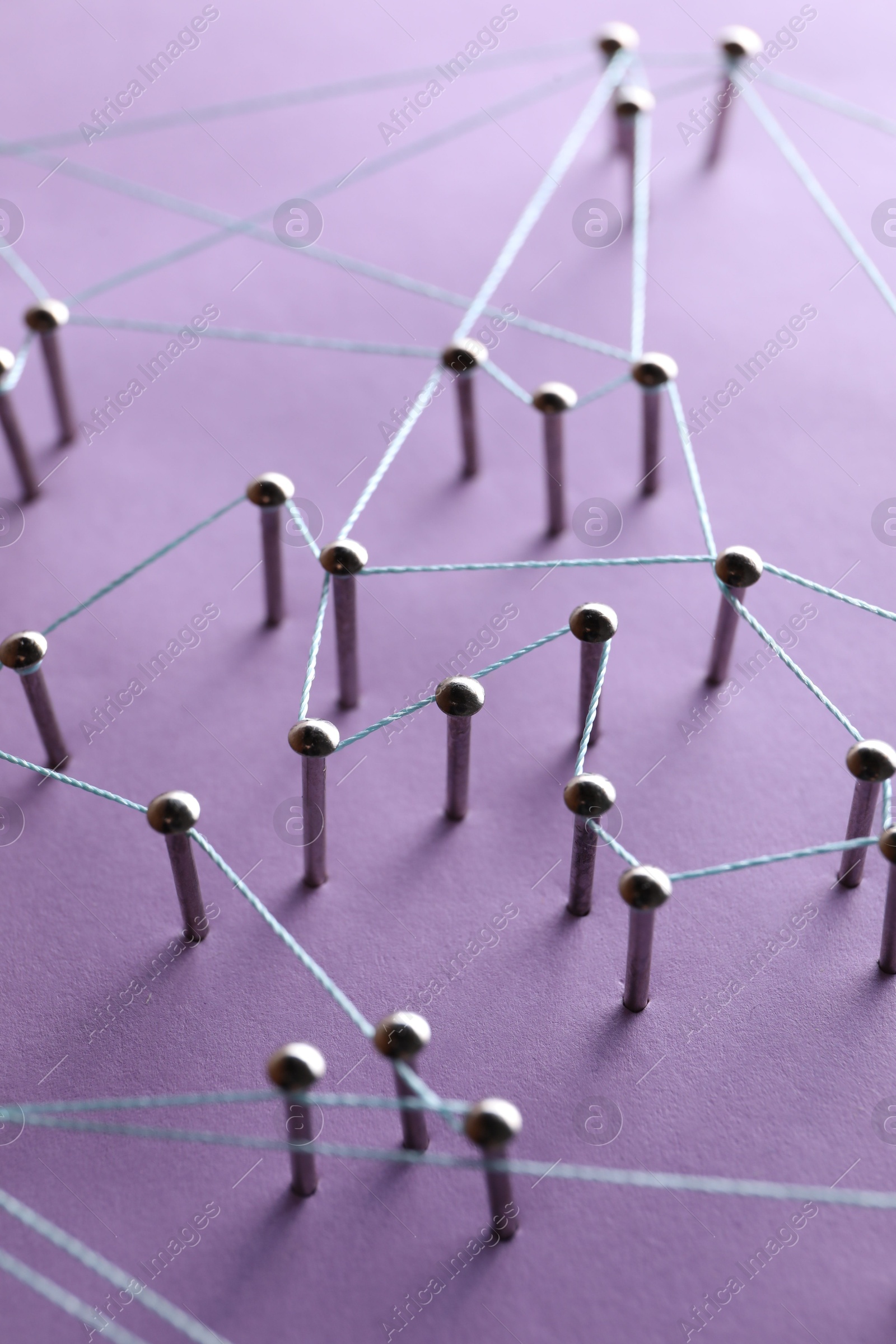 Photo of Network connection. Nails linked together by thread on violet background, closeup