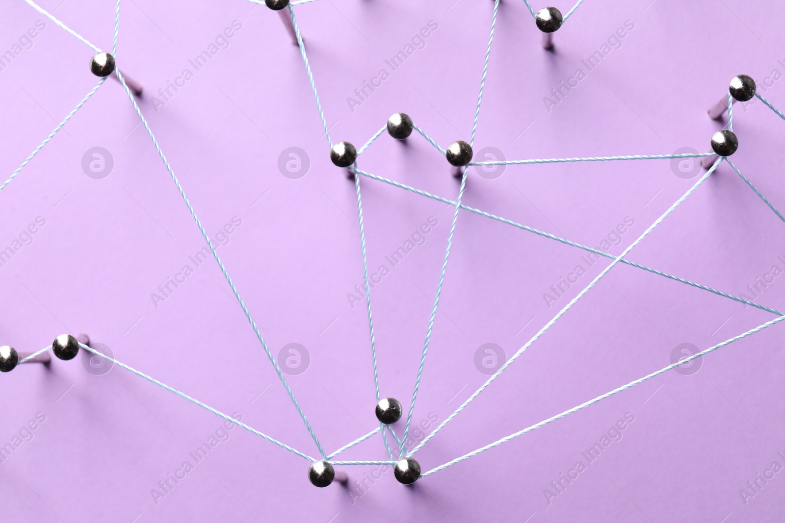 Photo of Network connection. Nails linked together by thread on violet background, flat lay