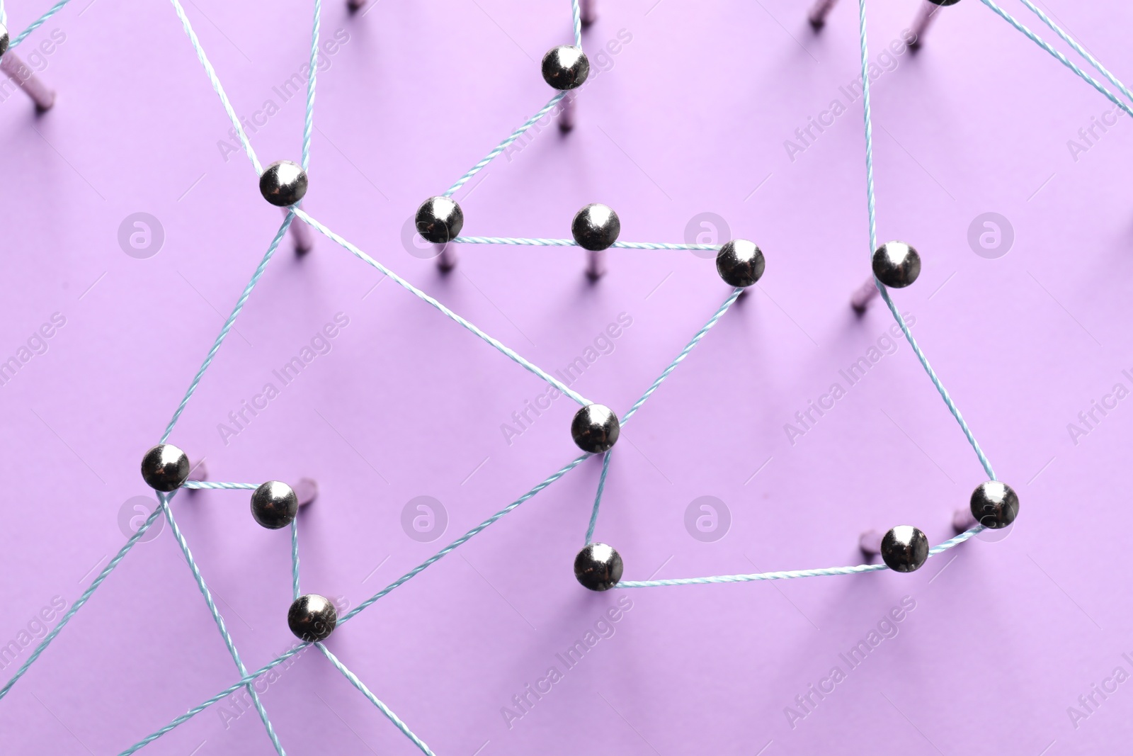 Photo of Network connection. Nails linked together by thread on violet background, flat lay