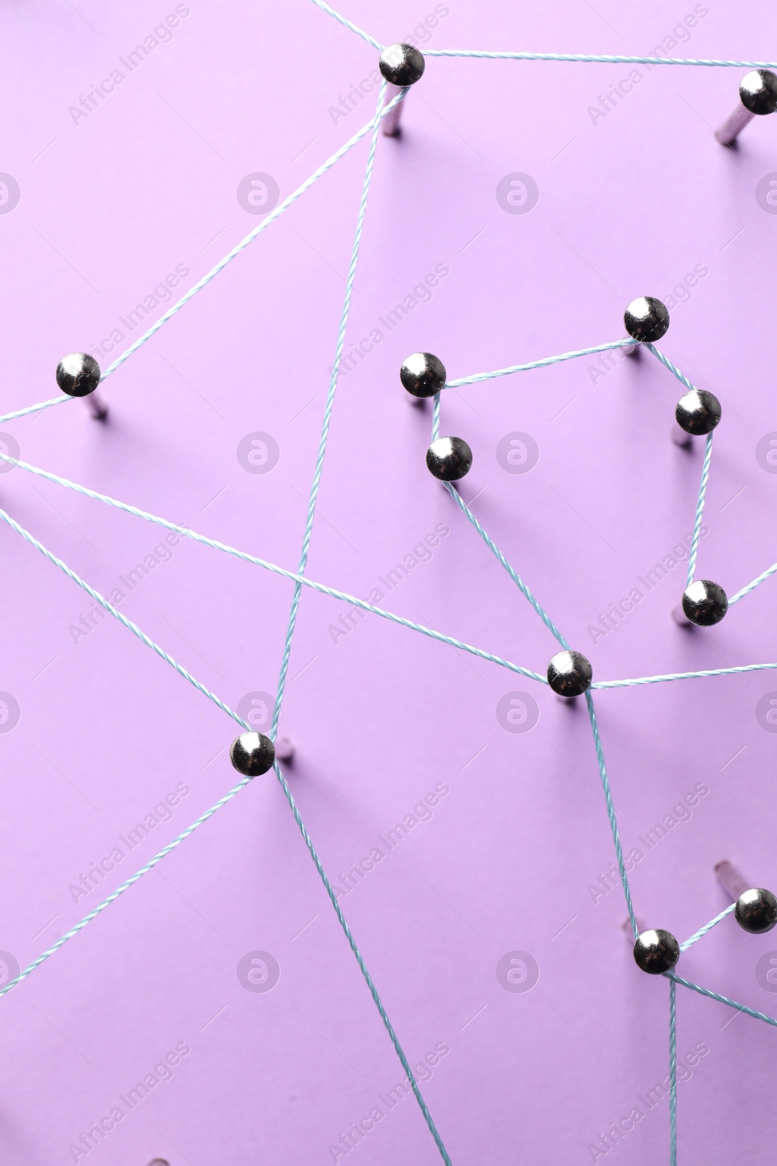 Photo of Network connection. Nails linked together by thread on violet background, flat lay