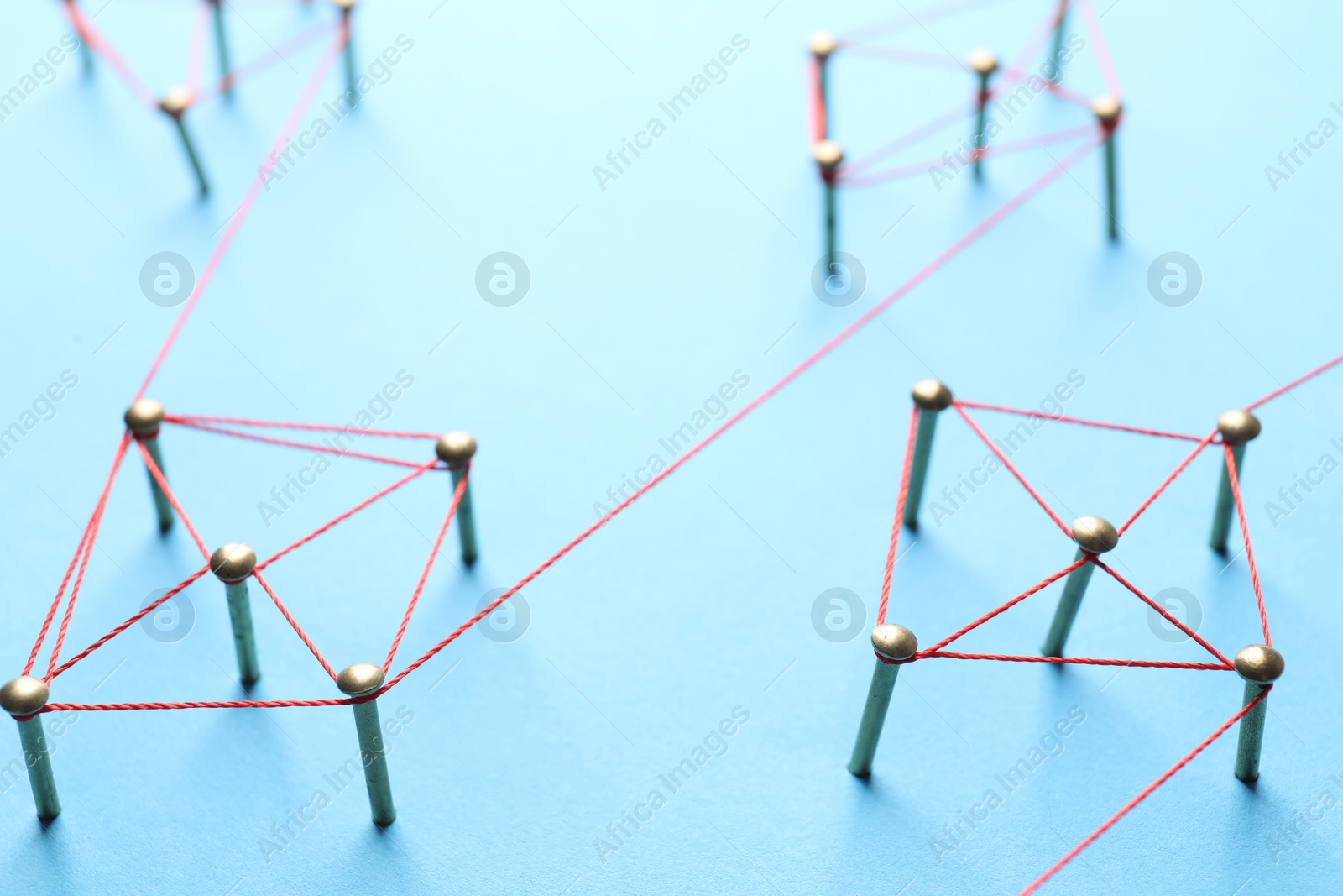 Photo of Network connection. Nails linked together by thread on light blue background, closeup