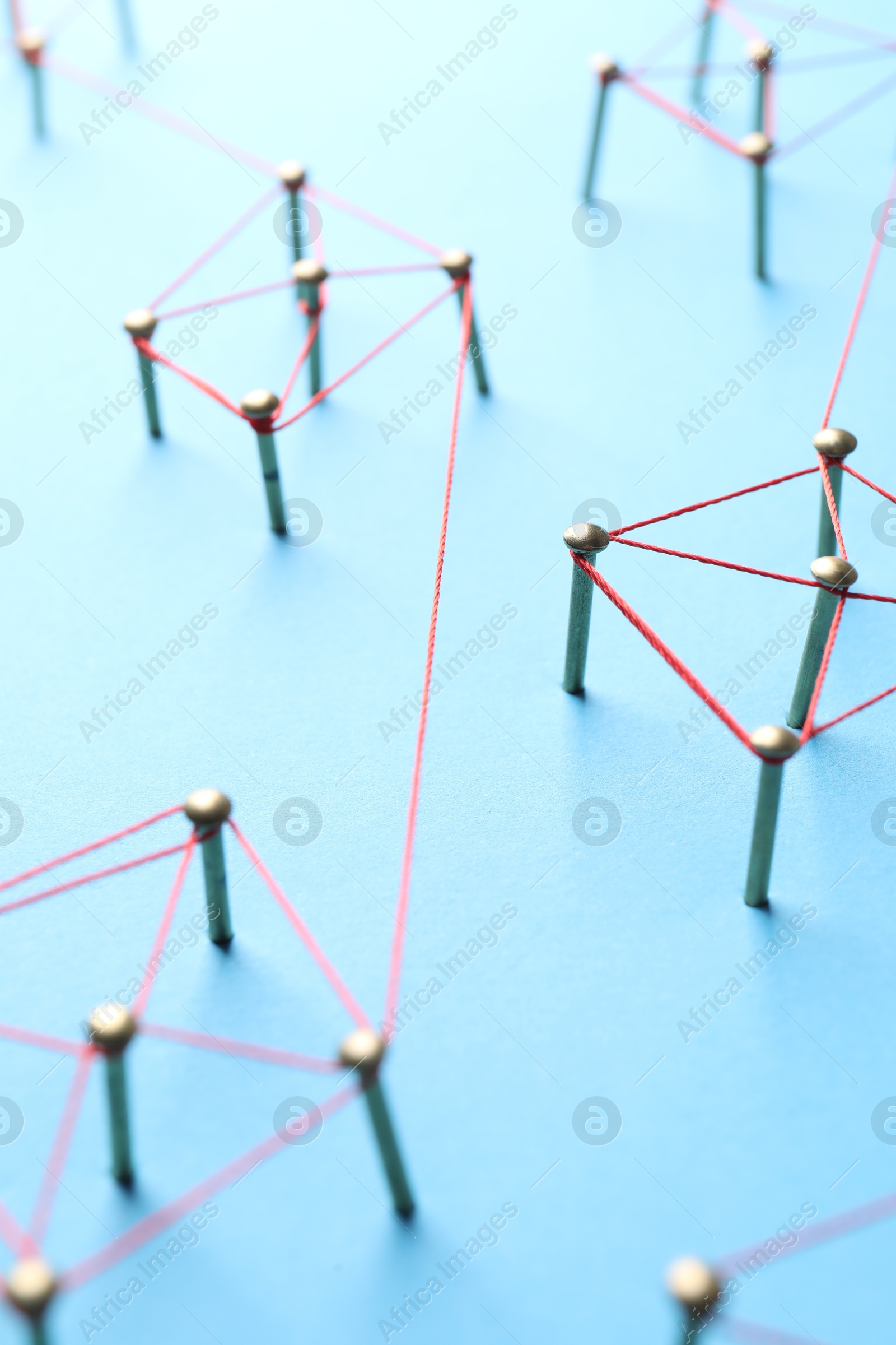 Photo of Network connection. Nails linked together by thread on light blue background, closeup