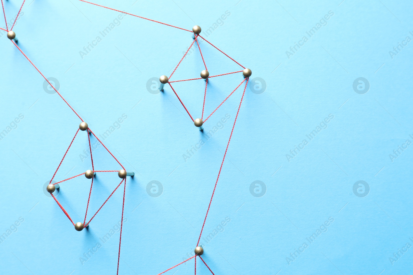 Photo of Network connection. Nails linked together by thread on light blue background, flat lay. Space for text