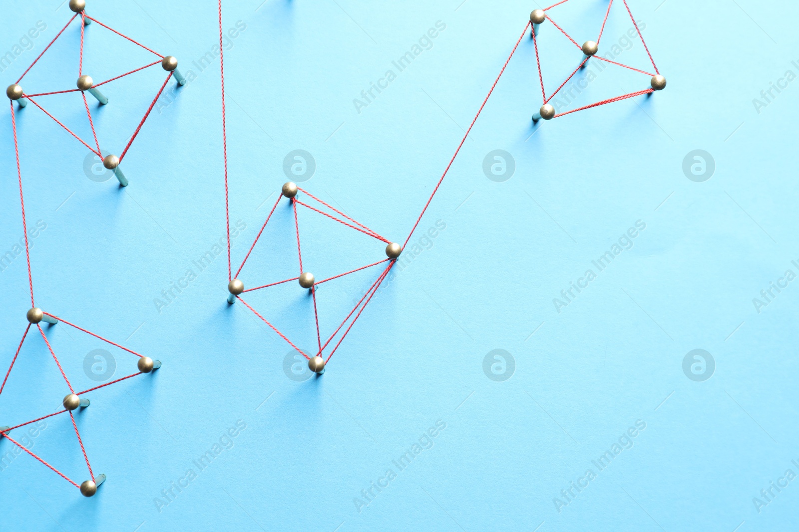 Photo of Network connection. Nails linked together by thread on light blue background, flat lay. Space for text