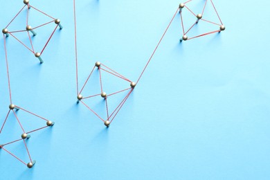 Photo of Network connection. Nails linked together by thread on light blue background, flat lay. Space for text