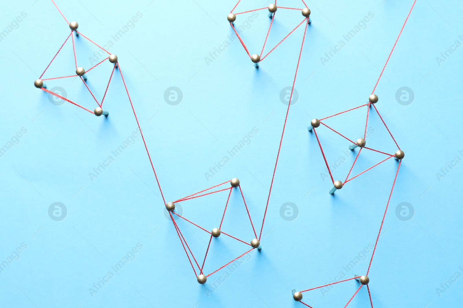 Photo of Network connection. Nails linked together by thread on light blue background, flat lay