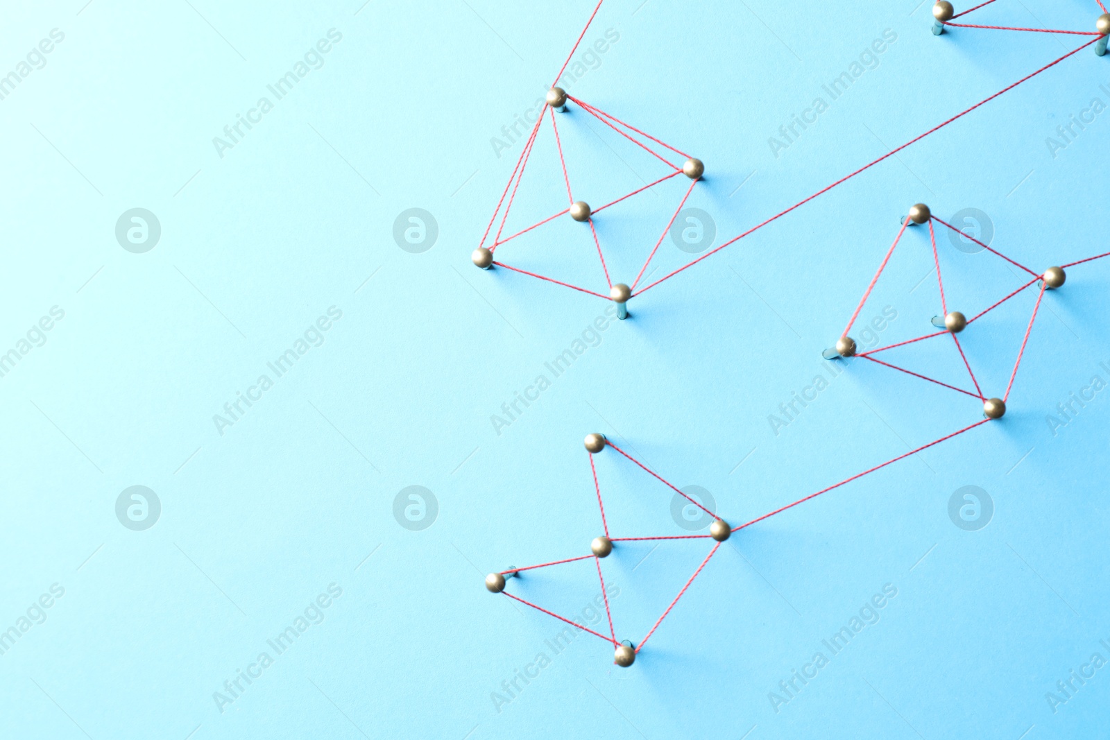 Photo of Network connection. Nails linked together by thread on light blue background, flat lay. Space for text