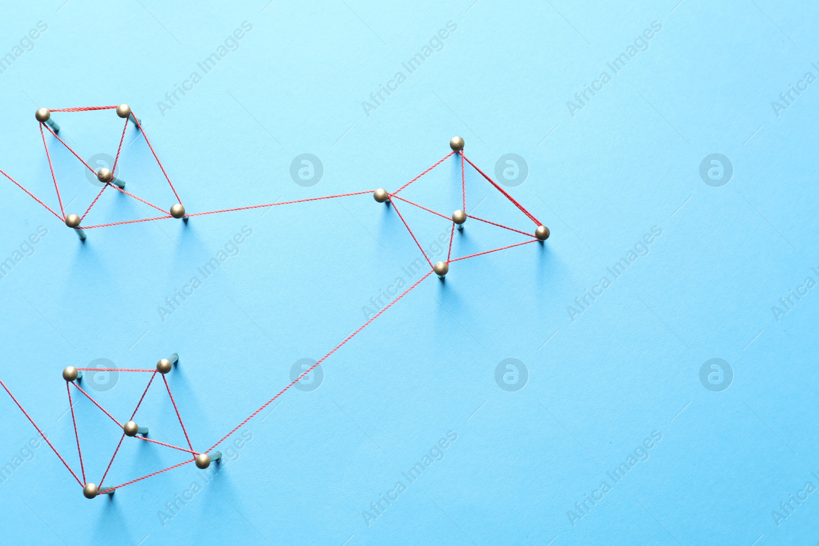 Photo of Network connection. Nails linked together by thread on light blue background, flat lay. Space for text