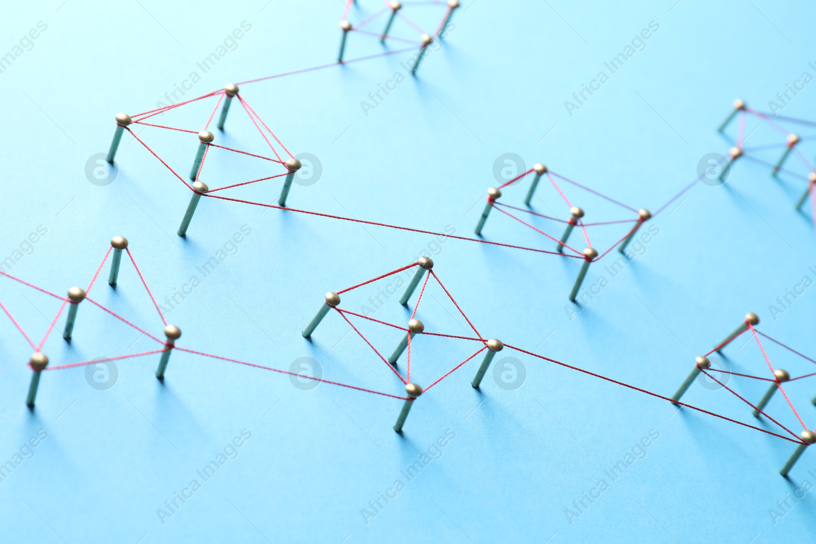 Photo of Network connection. Nails linked together by thread on light blue background, closeup