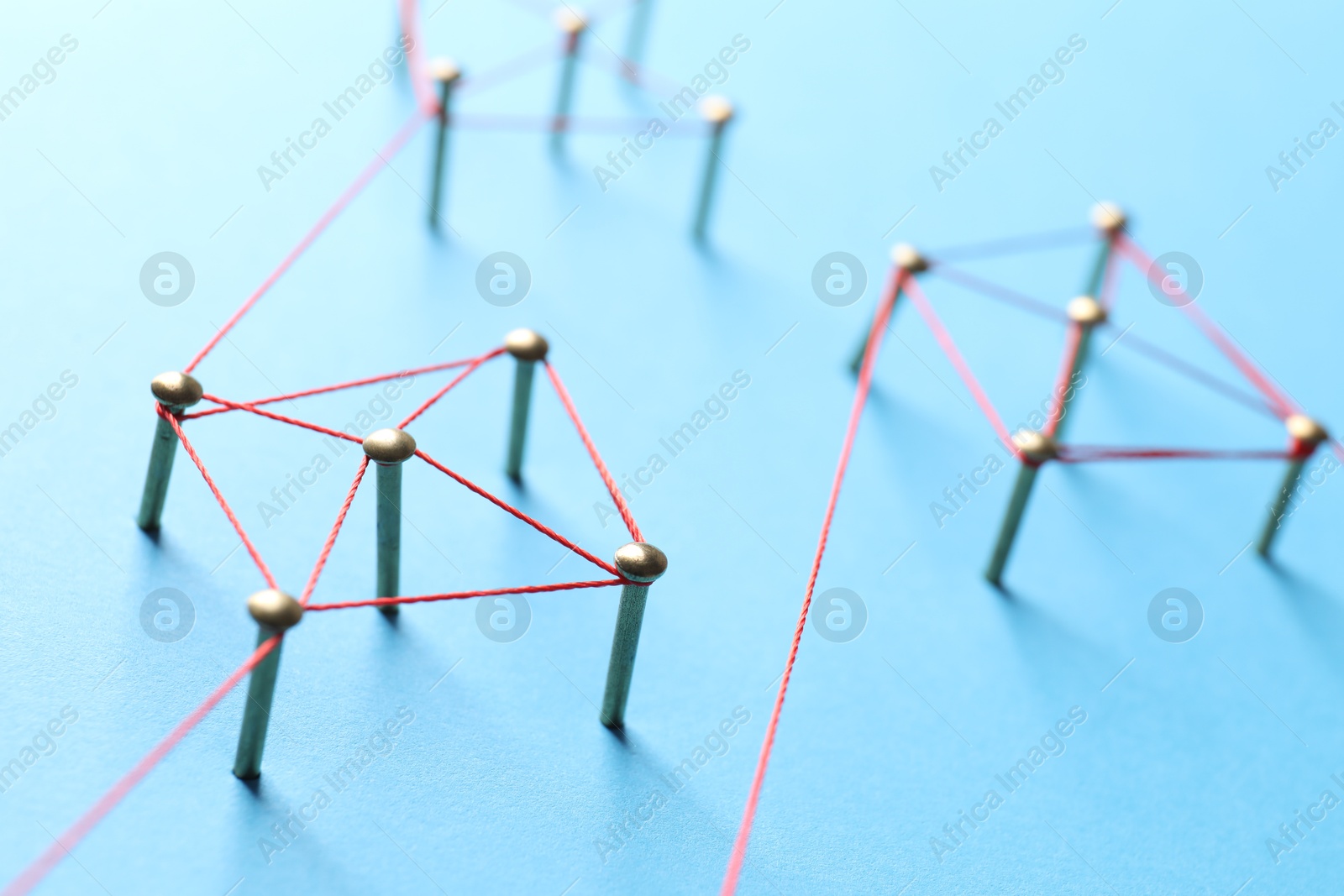 Photo of Network connection. Nails linked together by thread on light blue background, closeup