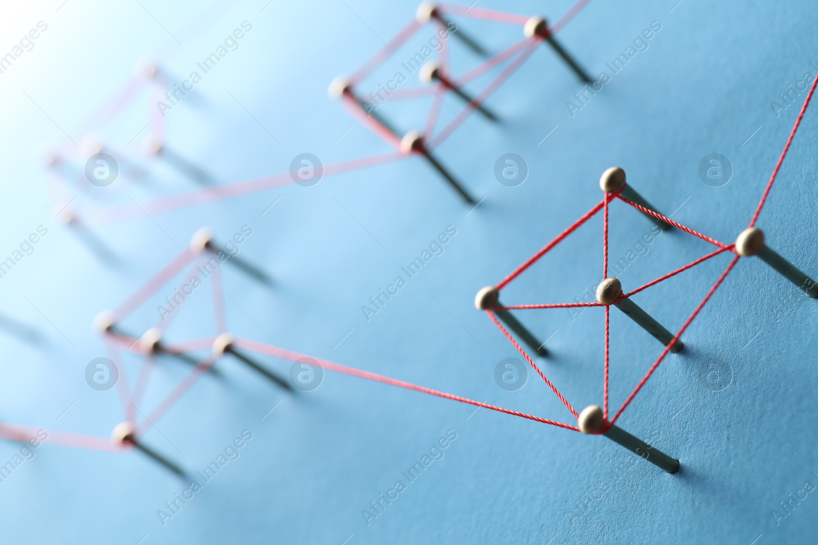 Photo of Network connection. Nails linked together by thread on light blue background, closeup