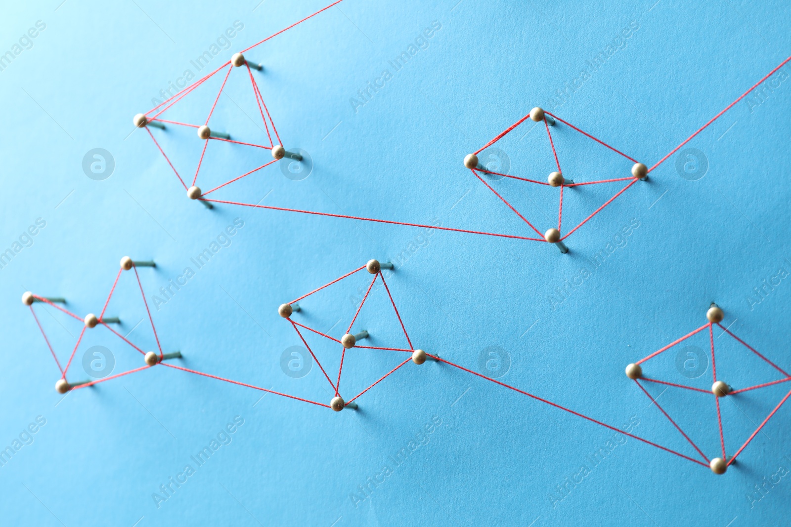 Photo of Network connection. Nails linked together by thread on light blue background, above view