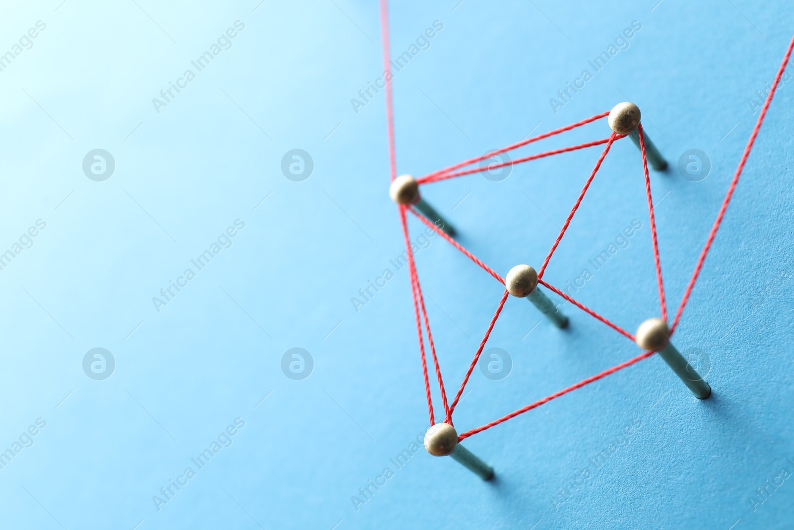 Photo of Network connection. Nails linked together by thread on light blue background, closeup. Space for text