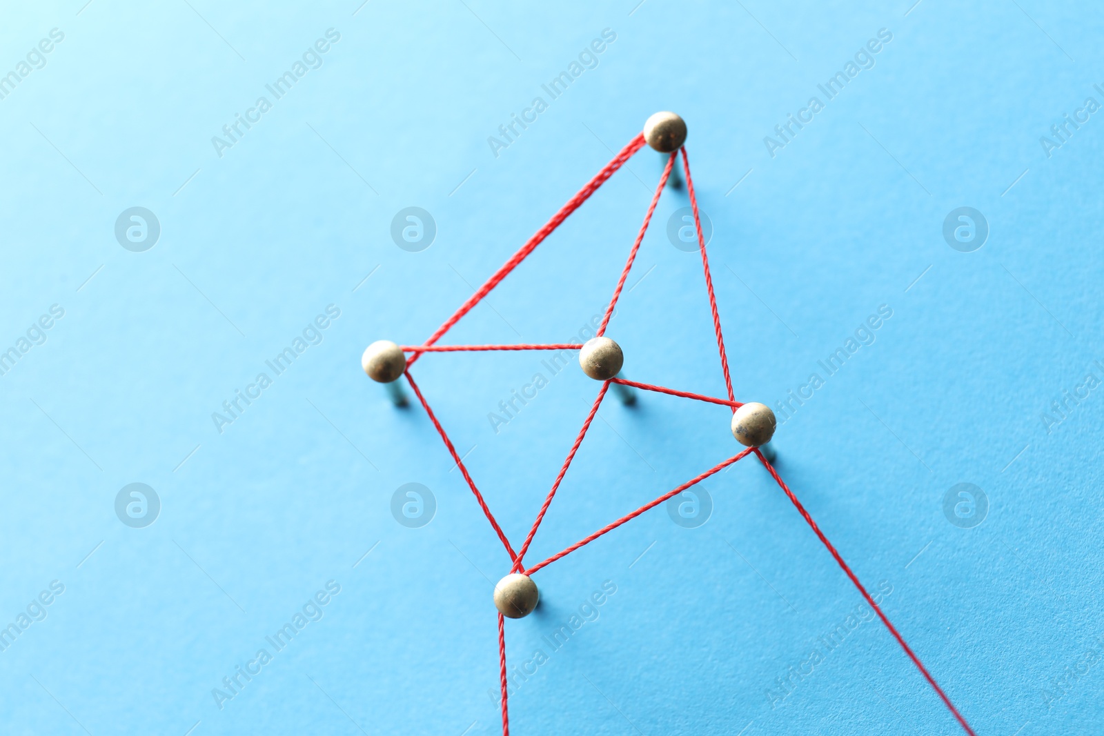 Photo of Network connection. Nails linked together by thread on light blue background, above view