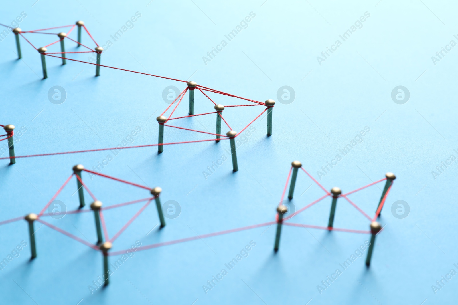 Photo of Network connection. Nails linked together by thread on light blue background, closeup