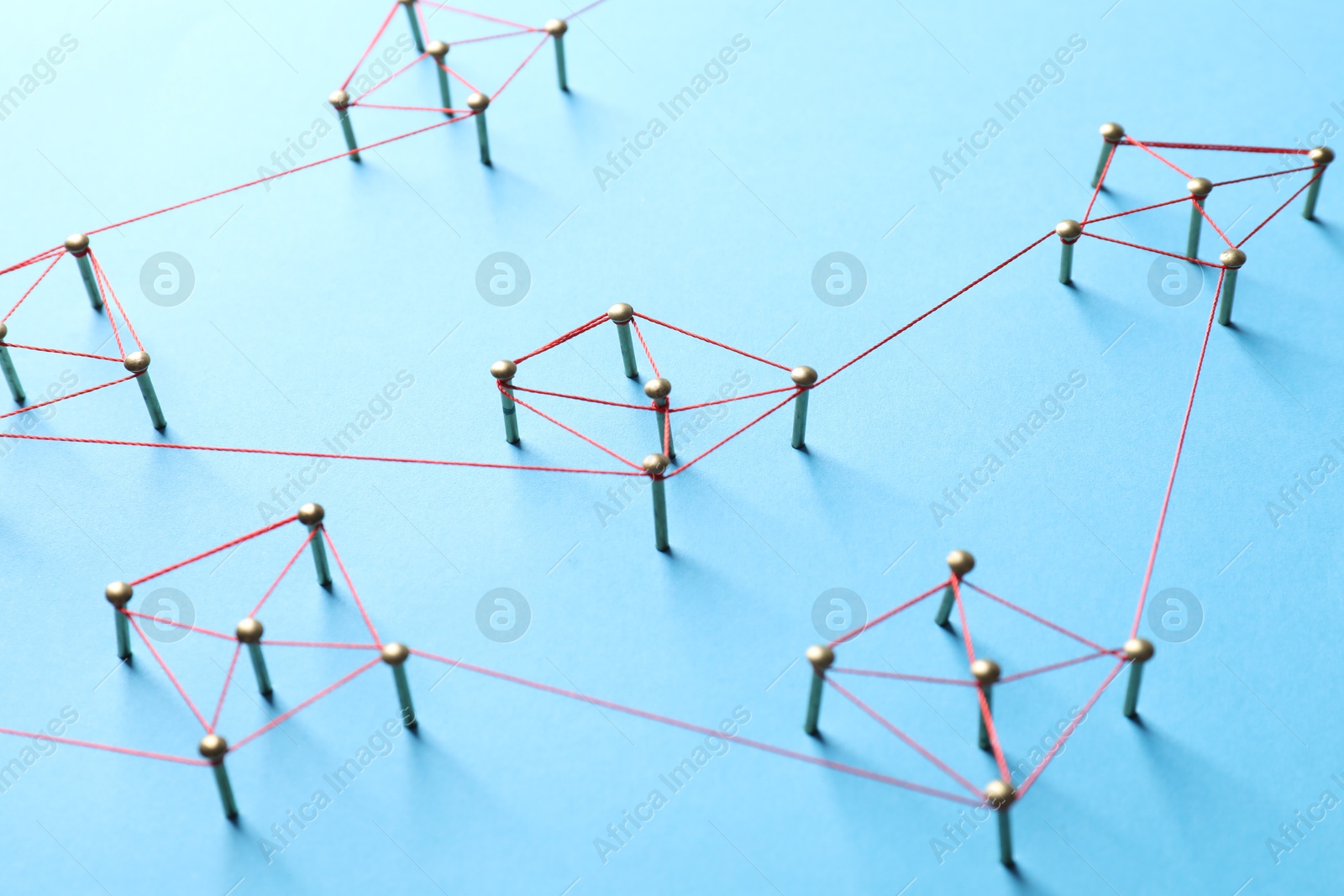 Photo of Network connection. Nails linked together by thread on light blue background, closeup