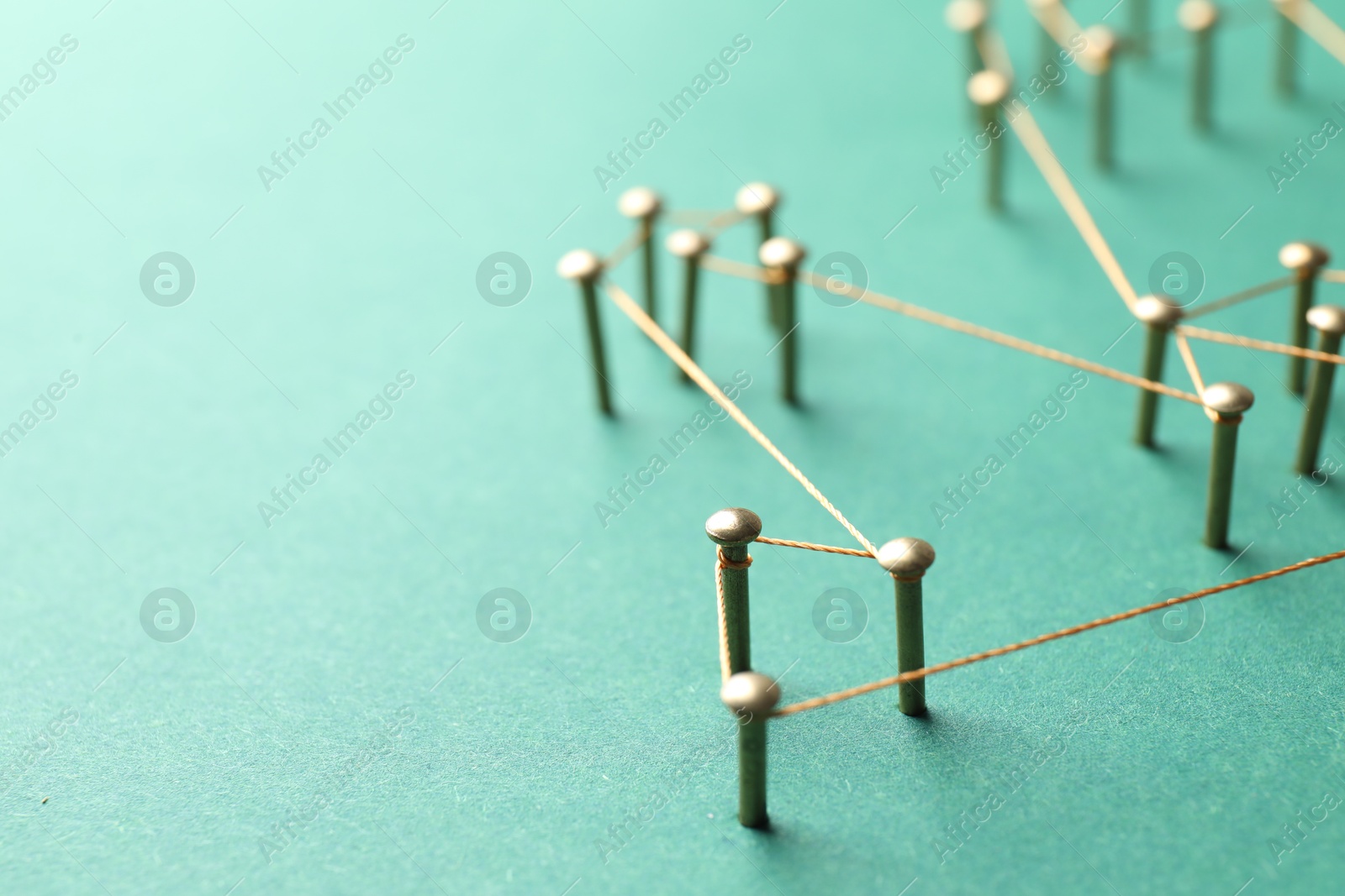 Photo of Network connection. Nails linked together by thread on green background, closeup. Space for text