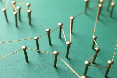 Photo of Network connection. Nails linked together by thread on green background, closeup