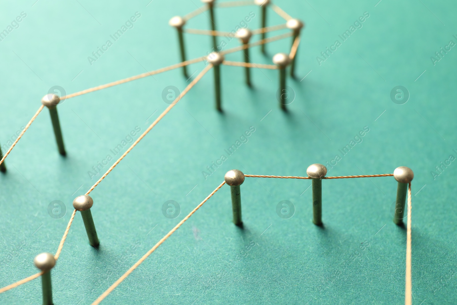 Photo of Network connection. Nails linked together by thread on green background, closeup