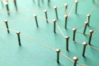 Photo of Network connection. Nails linked together by thread on green background, closeup