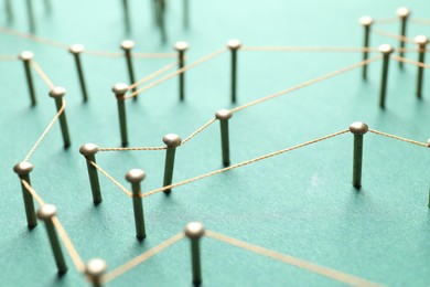 Photo of Network connection. Nails linked together by thread on green background, closeup