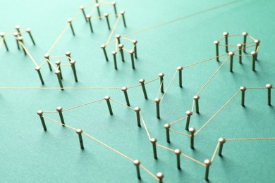 Photo of Network connection. Nails linked together by thread on green background, closeup