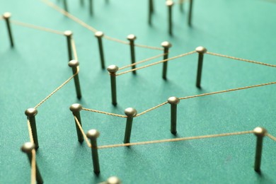 Photo of Network connection. Nails linked together by thread on green background, closeup