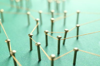 Photo of Network connection. Nails linked together by thread on green background, closeup