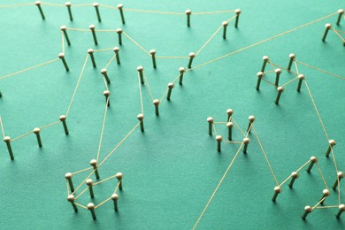 Photo of Network connection. Nails linked together by thread on green background