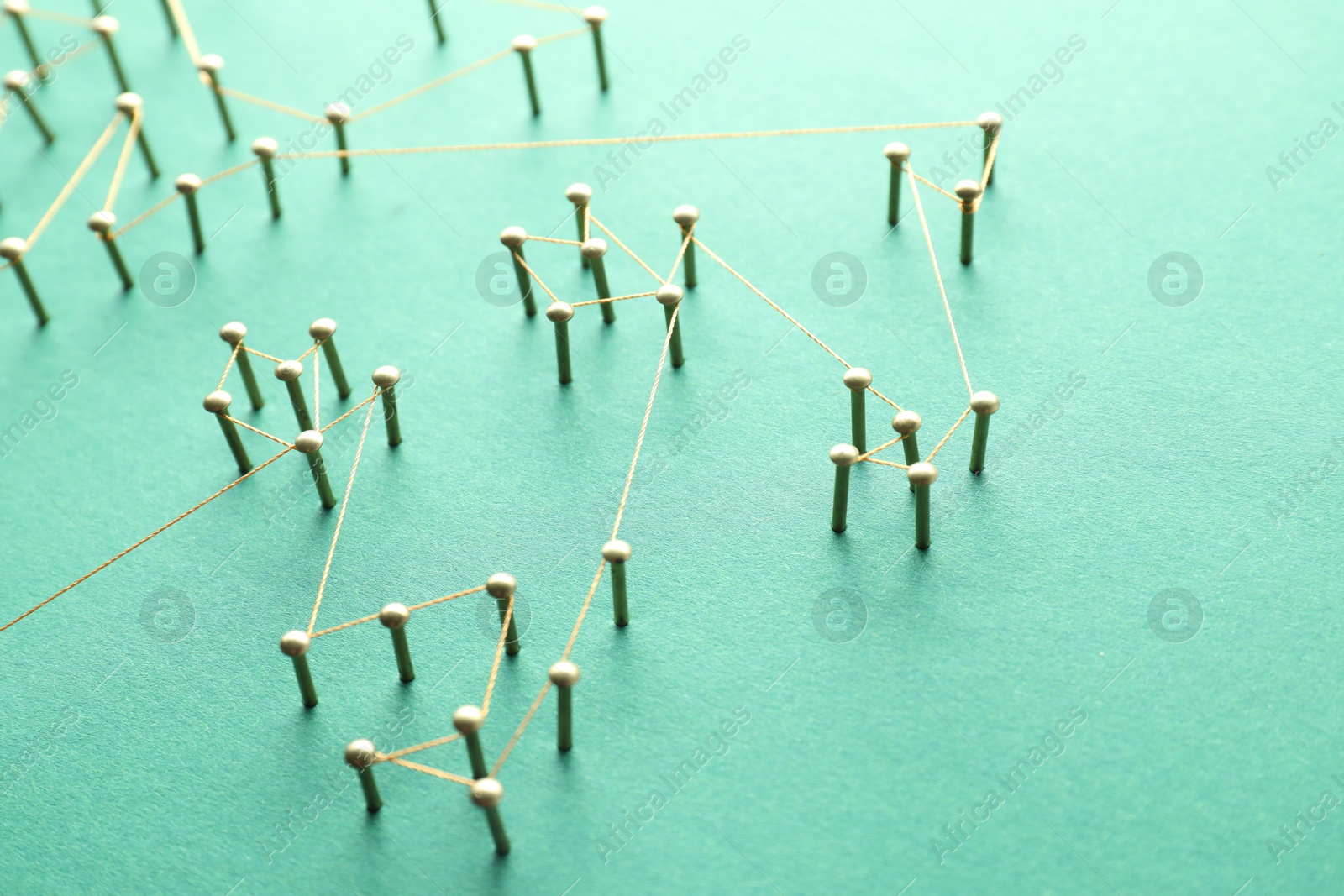 Photo of Network connection. Nails linked together by thread on green background, closeup