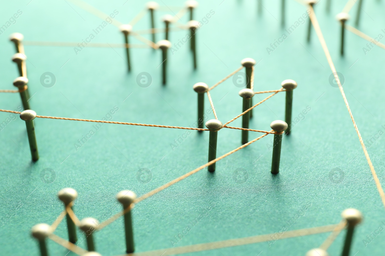 Photo of Network connection. Nails linked together by thread on green background, closeup