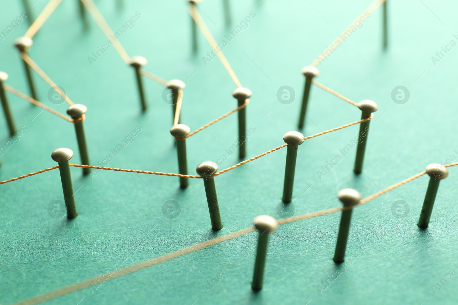 Photo of Network connection. Nails linked together by thread on green background, closeup