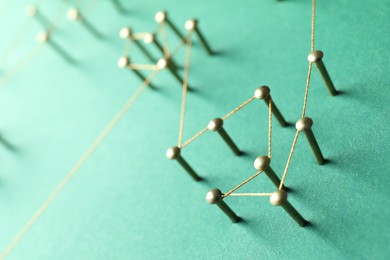 Photo of Network connection. Nails linked together by thread on green background, closeup. Space for text